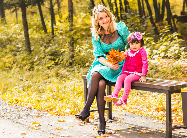 Klein meisje en haar moeder spelen in het herfstpark - Foto, afbeelding