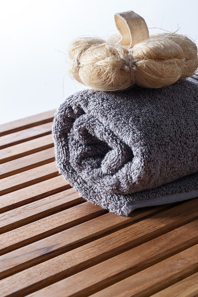 Loofah mitt voor het zuiveren van lichaamsverzorging op opgerolde handdoek - Foto, afbeelding