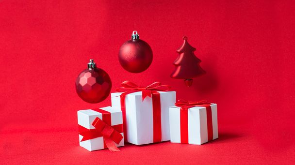Белая подарочная коробка с красной лентой и мячом на Рождество
 - Фото, изображение