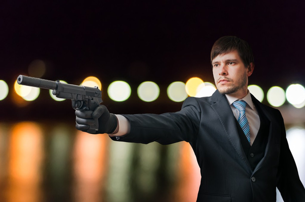 Agent or hitman is aiming with pistol with silencer at night. - Photo, Image