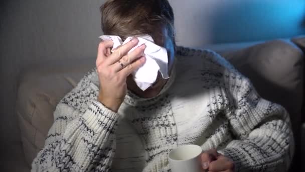 Uomo malato che soffia il naso nel tessuto, giovane malato a letto che tiene il naso moccioso per la pulizia dei tessuti con temperatura che si sente male infettato dal virus dell'influenza e dal concetto di assistenza sanitaria influenzale
 - Filmati, video