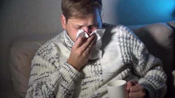 Zieke man zijn neus waait in het weefsel, jonge zieke man in bed holding weefsel schoonmaken snotterig neus met temperatuur gevoel slecht septisch tegen winter grippe virus in griep en influenza gezondheidszorg concept - Video