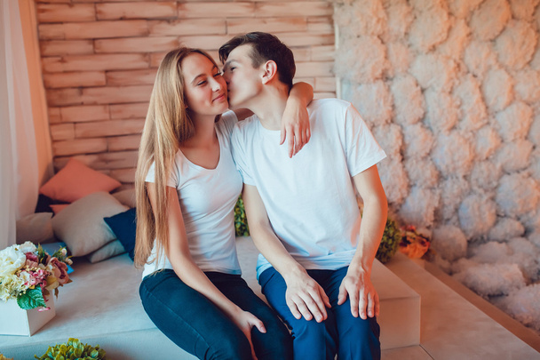 junges verliebtes Paar sitzt und Mann küsst Mädchen auf die Wange - Foto, Bild