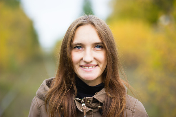 Portrait of young cute woman in fall autumn park. Beautiful caucasian girl walking in forest, close up - Photo, Image