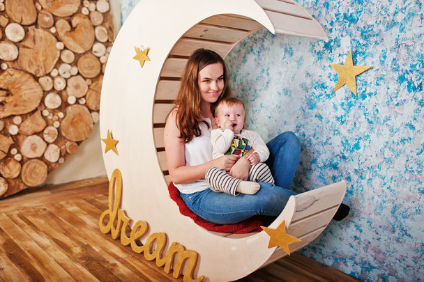 Young caucasian mother and her baby boy sitting on decorated moo - Foto, Bild