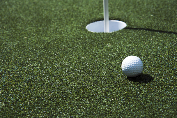 μπάλα του γκολφ και τρύπα σε ένα πεδίο - Φωτογραφία, εικόνα