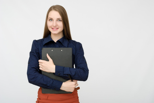 Portrait of smiling business woman with pen and paper folder. Young pretty worker writing something in her papers - Foto, imagen
