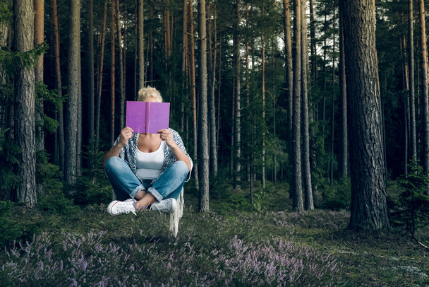Jovem mulher bonita lendo um livro e levita na floresta
 - Foto, Imagem