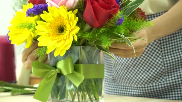 Квіткова жінка закінчила розстановку квітів за допомогою зав'язування стрічки на скляній вазі
 - Кадри, відео