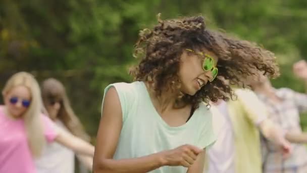 Νεαρή γυναίκα με σγουρά μαλλιά χορεύει, κουνώντας το κεφάλι του στο φεστιβάλ μουσικής, αργή κίνηση - Πλάνα, βίντεο