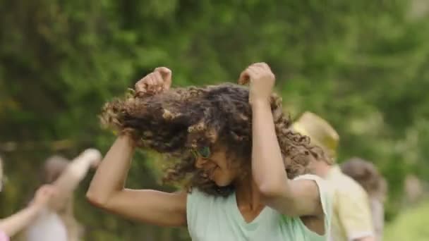 attraktive Mischlingsfrau, die Haare schüttelt, zur Musik tanzt, für die Kamera lächelt - Filmmaterial, Video