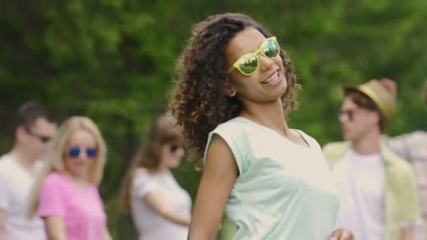 junge hübsche Frau mit lockigem Haar tanzt beim Picknick mit Freunden, Sommer - Filmmaterial, Video