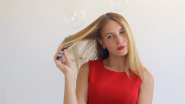 Young cute blonde girl with hairbrush - Felvétel, videó