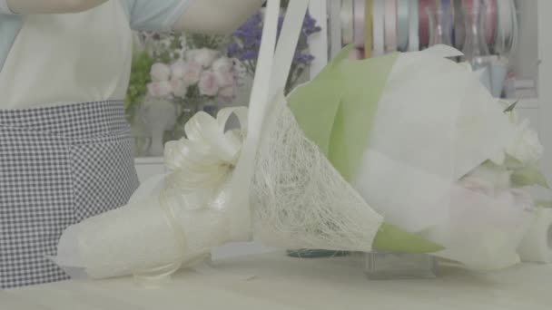 Blumenhändlerin bindet Schleife an einem schönen Blumenstrauß, ungraded Ton - Filmmaterial, Video