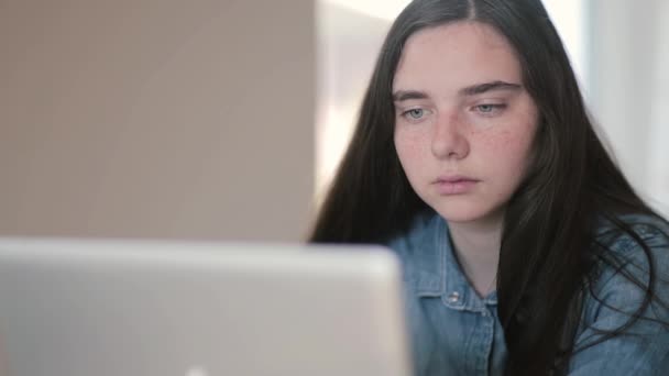 Close-up portrait of teenage girls using a laptop sitting at table at home - Imágenes, Vídeo