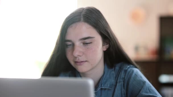 Close-up portrait of teenage girls using a laptop sitting at table at home - Materiał filmowy, wideo