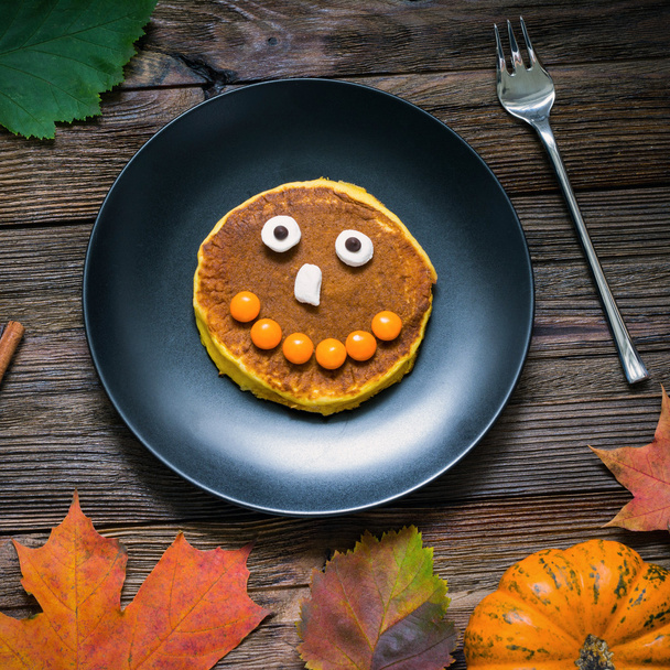 Cute halloween food: pumpkin pancake with candy face for children - Foto, Imagen
