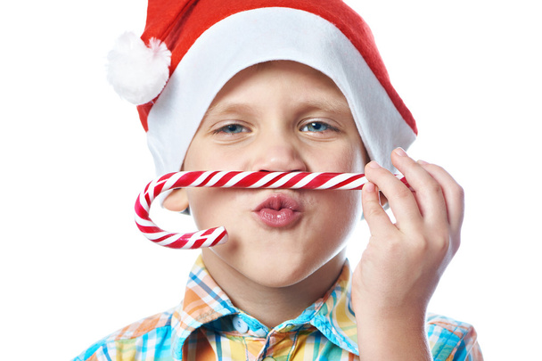 Little boy in New Year's red cap with Christmas candy cane isola - Φωτογραφία, εικόνα