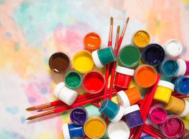 Paints, brushes and palette on the colorful background. - Фото, изображение