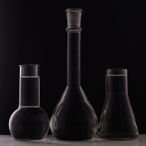 Equipo de laboratorio, tres frascos de vidrio sobre fondo negro
 - Foto, imagen