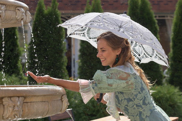 girl at the fountain with white umbrella - Photo, Image
