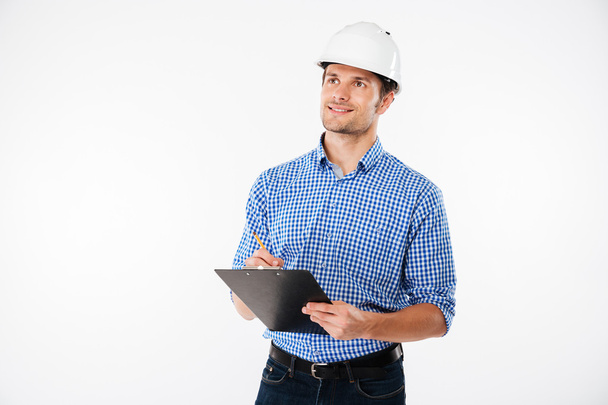 Man building engineer in hard hat writing on clipboard - Fotografie, Obrázek