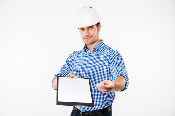 Confident young man building engineer in helmet holding blank clipboard - Photo, image