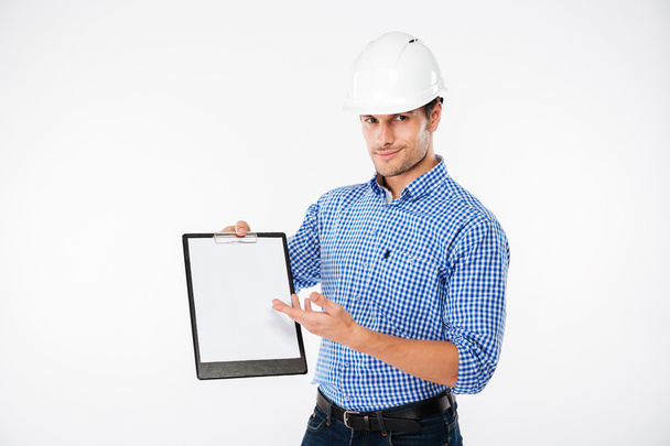 Инженер-строитель в каске указывает на пустой блокнот
 - Фото, изображение