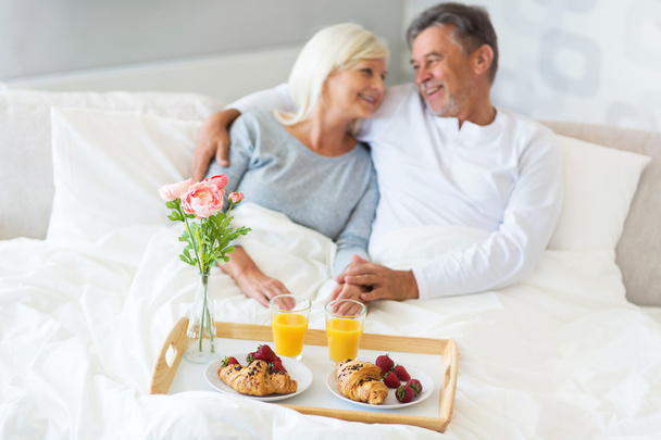 Senior couple enjoying breakfast in bed - 写真・画像