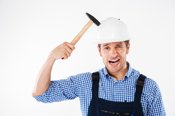Builder applying hummer to his head in helmet - Foto, afbeelding