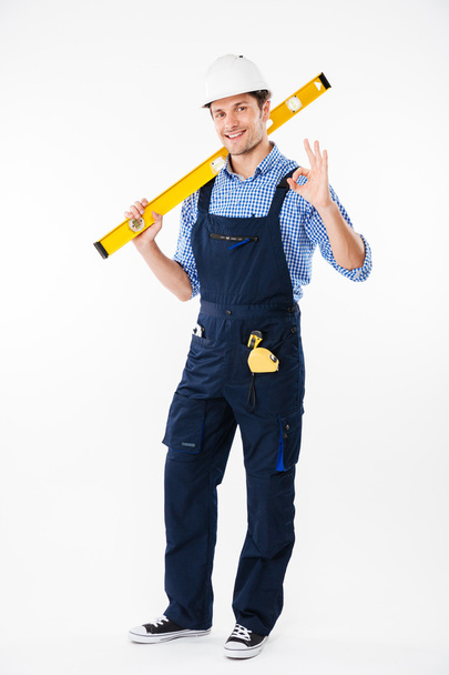 Portrait of a smiling builder standing and showing okay gesture - Foto, imagen