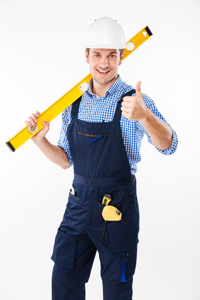 Smiling male builder standing and showing thumbs up gesture - Fotoğraf, Görsel