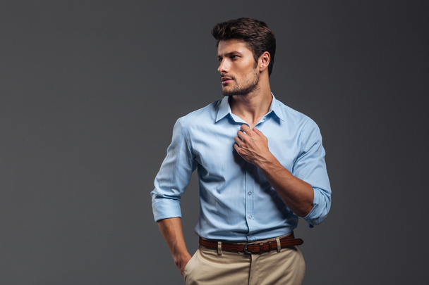 Portrait of a casualman buttoning his shirt isolated - Foto, immagini