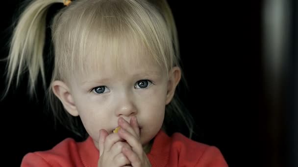 Nahaufnahme eines kleinen blonden Mädchens, das eine Scheibe Orange isst - Filmmaterial, Video