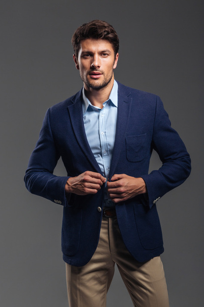 Portrait of a casual handsome man buttoning his jacket - Foto, Bild
