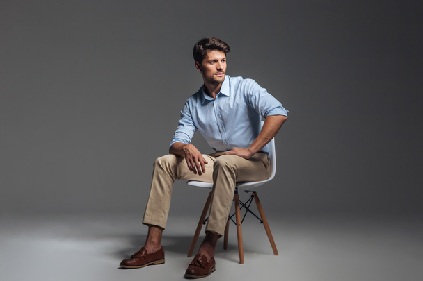 Pensive brunette man in blue shirt sitting on the chair - Foto, immagini