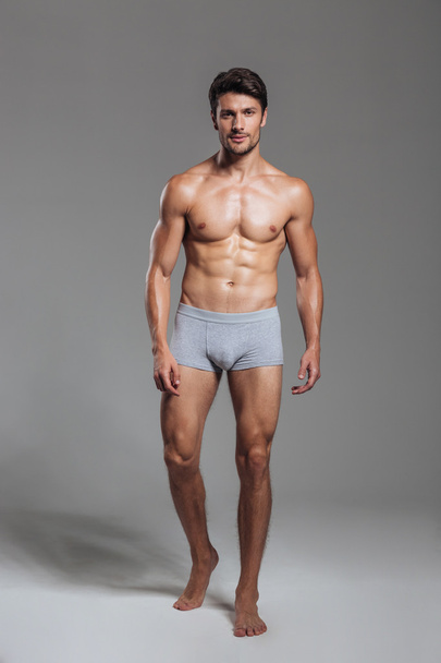 Portrait of a happy muscular man in underwear standing - Фото, изображение