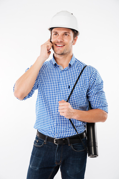 Cheerful man architect in building helmet talking on cell phone - Foto, Imagen
