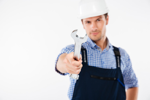 Close up portrait of a serious handsome builder holding wrench - Fotoğraf, Görsel
