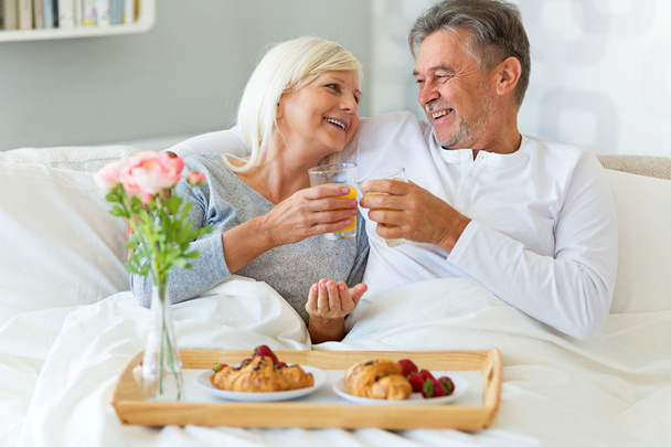 Senior couple enjoying breakfast in bed - Фото, изображение