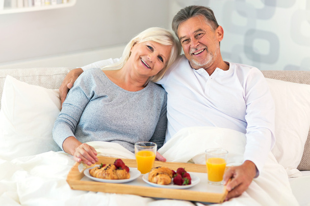 Senior couple enjoying breakfast in bed - Valokuva, kuva
