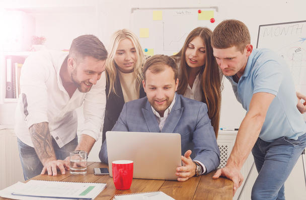 Счастливые деловые люди объединяются возле ноутбука в офисе
 - Фото, изображение
