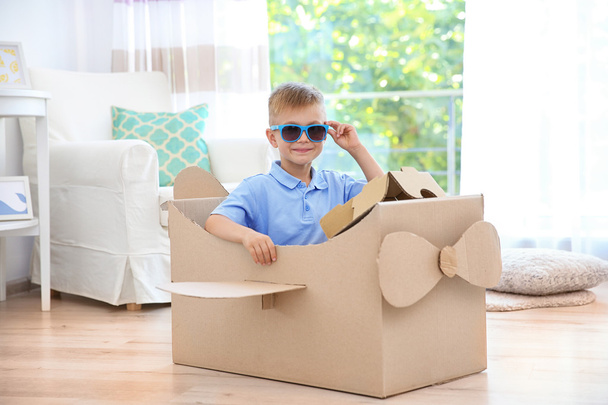 Little boy playing with cardboard airplane indoors - Фото, изображение
