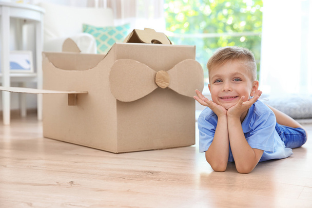 Little boy playing with cardboard airplane indoors - Φωτογραφία, εικόνα