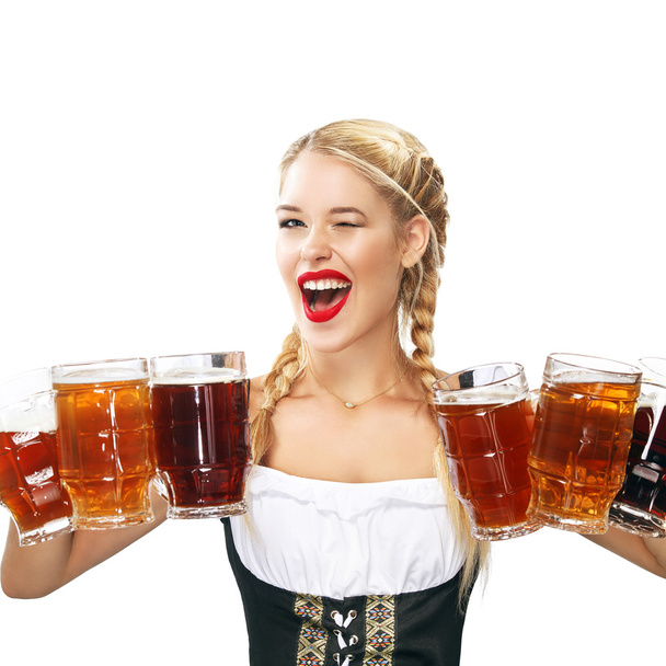 Joven camarera sexy Oktoberfest, con un vestido tradicional bávaro, sirviendo tazas de cerveza grandes aisladas sobre fondo blanco
. - Foto, imagen