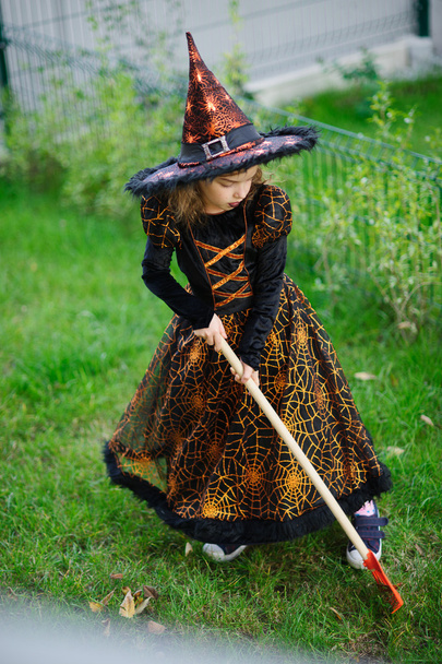 Preparation for Halloween. The girl in suit of the evil witch cleans a lawn rake - Foto, imagen