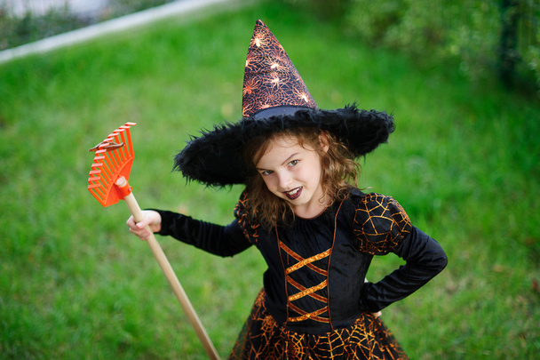 Felkészülés Halloween. A lány ruha, a gonosz boszorkány tisztítja a kerti gereblye - Fotó, kép