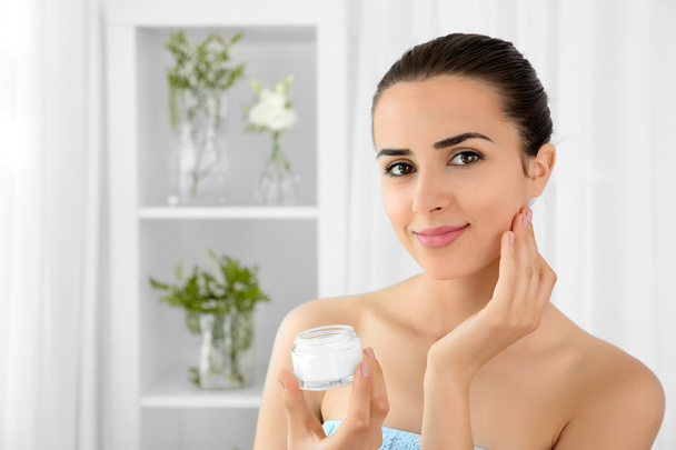 Portrait of young woman holding facial cream - Photo, Image