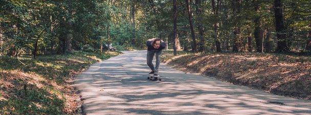 Skateboarder ride a longboard through the forest , panorama - Photo, image