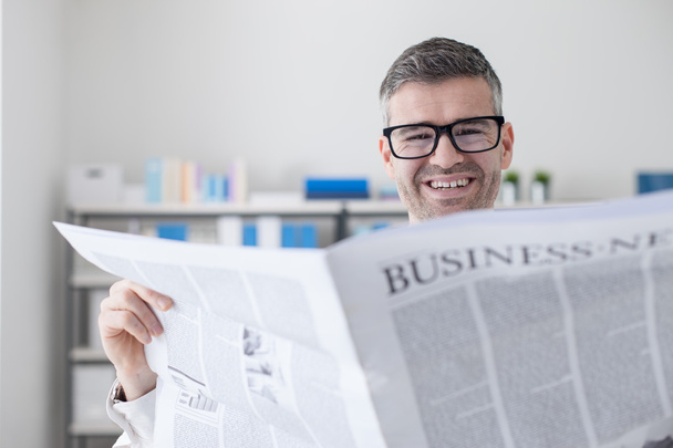 Confident businessman reading a newspaper - Фото, зображення